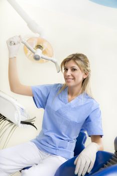 dental assistant smiling and adjusting the lamp