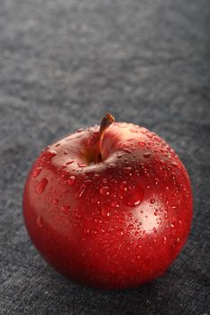 red apple with drops of water on blue denim background