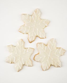 Three snowflake sugar cookies with decorative icing.