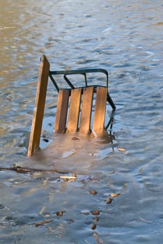 a bench which is thrown in the lake by vandals and frozen in the water