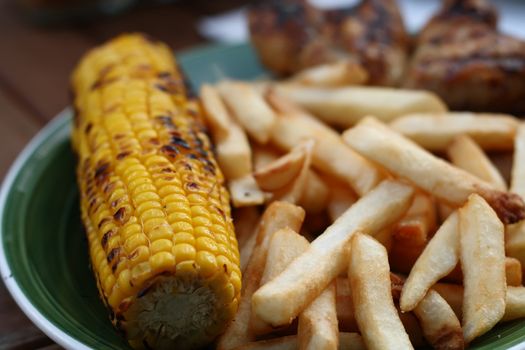 grilled sweet corn and potato fries on plate