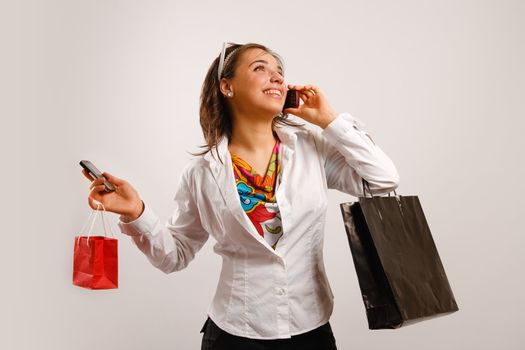 Attractive beautiful young woman talking at the phone and holding shopping bags