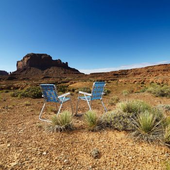 Two lawn chairs in scenic desert landscape with butte landformation.