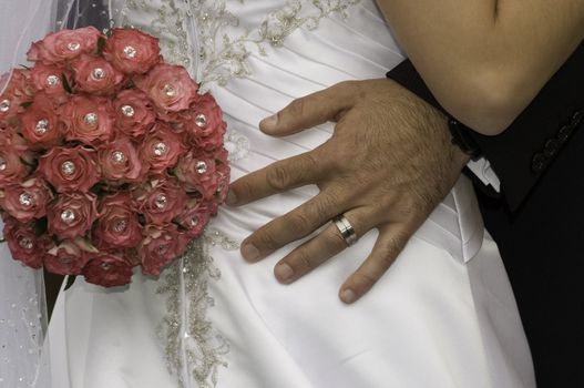 groom standing with his hand red bouquet on his brides bum