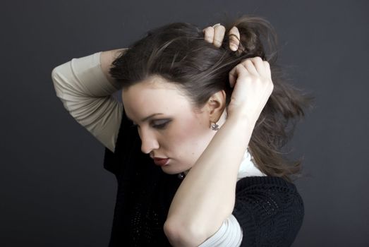Portrait of a young  beautiful  fashionable brunette  making a hair-do