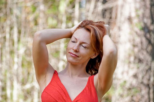 Portrait of red-haired adult woman in nature