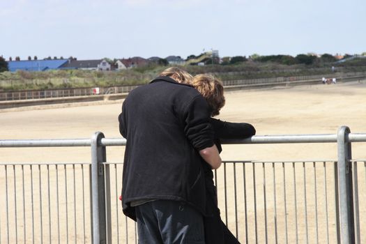 courting couple having a kiss and cuddle next to a railing