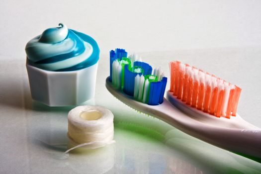 Toothpaste squeezed from tube onto cap with toothbrushes and floss