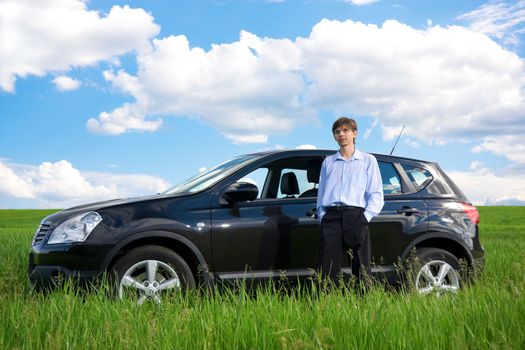 Successful businessman with car on grassland