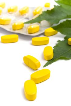 yellow vitamin pills and green leaves