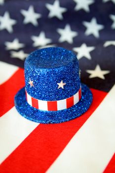 A top hat of blue glitter along with stars and stripes.  American flag is used as the background.