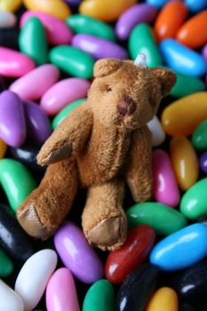 A miniature Teddy bear sitting amongst Jelly Beans