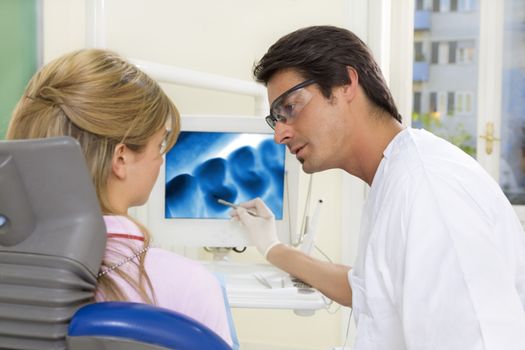 dentist talking to his patient and showing her a x-ray image of her teeth