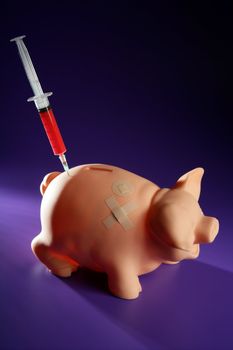 piggy bank with syringe, financial metaphor