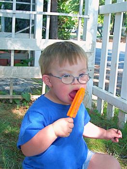 Boy with Downs Syndrome eating  a popsicle.