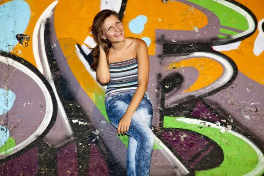 Beautiful girl near graffiti wall background.