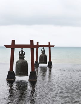 Two old large bells in water with sea-view