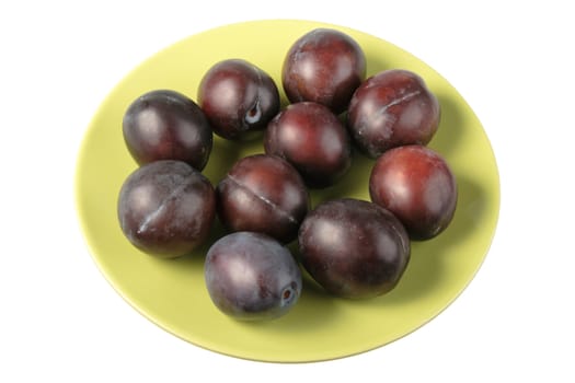 Group of dark-purple plums on plate. Close-up. Isolated on white background.