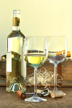 Still life of white wine bottle and glasses with crate