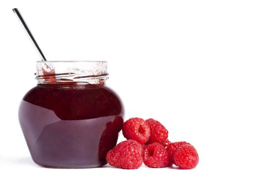 jam jar with a spoon and raspberries aside 