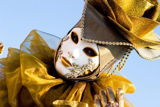 A venetian woman in a gold costume with a white mask