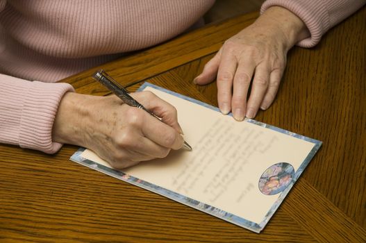 senior woman writing a letter with pen and paper