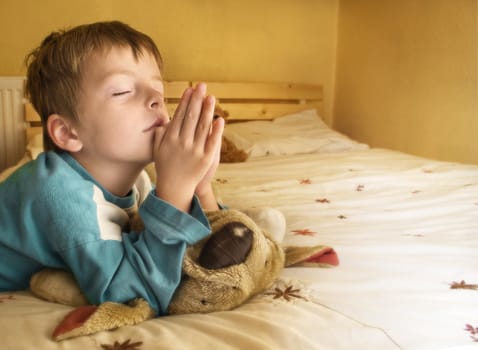 Little boy praying at bedtime.