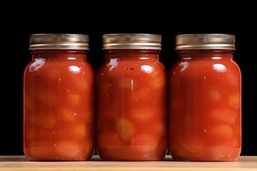 Three jars of canned tomatoes lined in a row