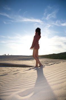 sexy woman on dune against sun
