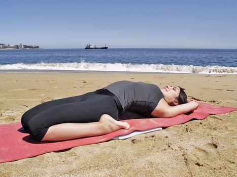 Bikram yoga supta bajrasana pose at beach