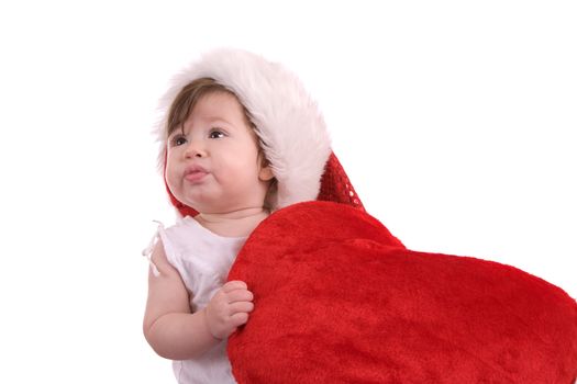 Cute little baby wearing a santa hat and holding on to a large red heart