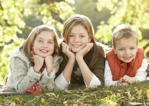 Group Of 3 Children Realxing Outdoors In Autumn Landscape