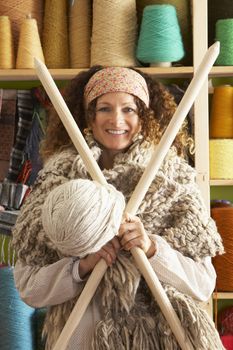 Woman Wearing Knitted Scarf Standing In Front Of Yarn Display Ho
