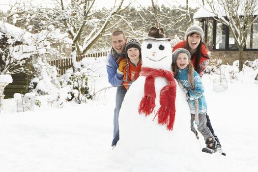 Family Building Snowman In Garden