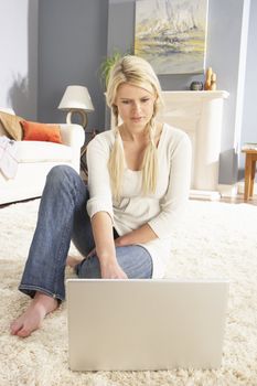 Woman Using Laptop To Manage Household Bills Laying On Rug At Ho