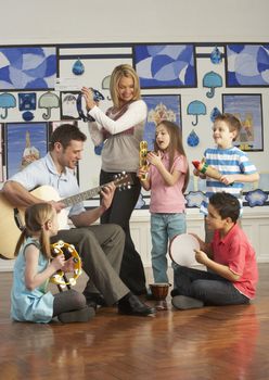 Teachers Playing Guitar With Pupils Having Music Lesson In Class