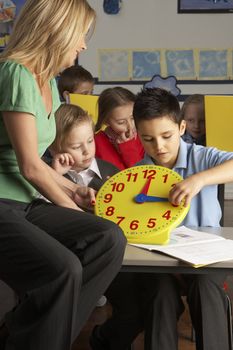 Female Teacher In Primary School Teaching Children To Tell Time 
