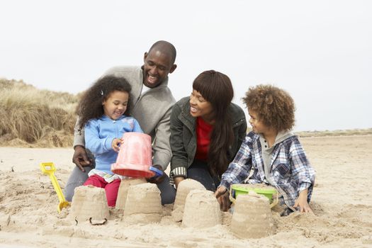 Young Family Building Sandcastle On Beach Holiday