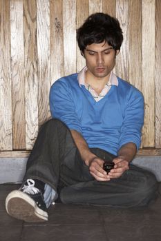 Young man sitting on floor with mobile phone