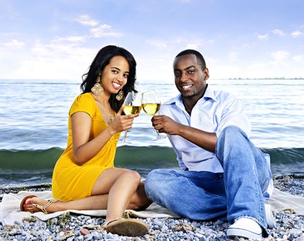 Young romantic couple celebrating with wine at the beach