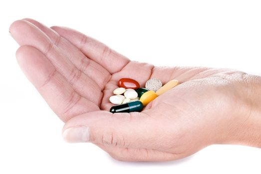 hand with various pills over white background