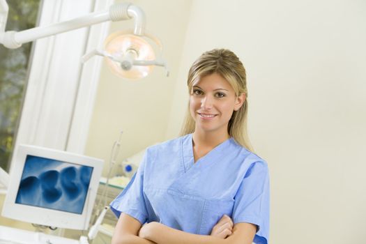 young dental assistant smiling. X-ray image on the computer monitor in the background