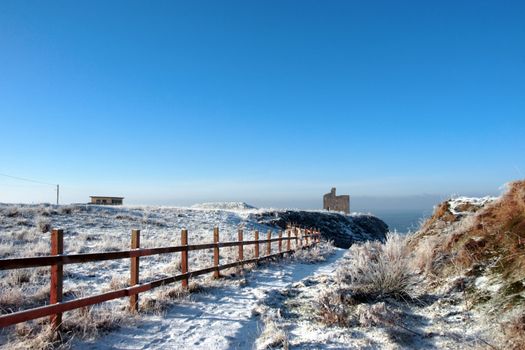 fenced walk to ballybunion castle in winter snow
