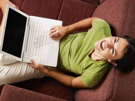 woman with pc laughing on sofa