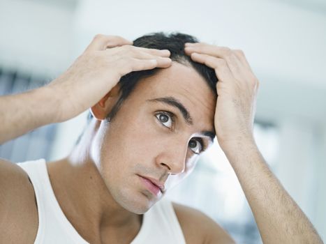 caucasian adult man checking hairline. Horizontal shape, head and shoulders, front view