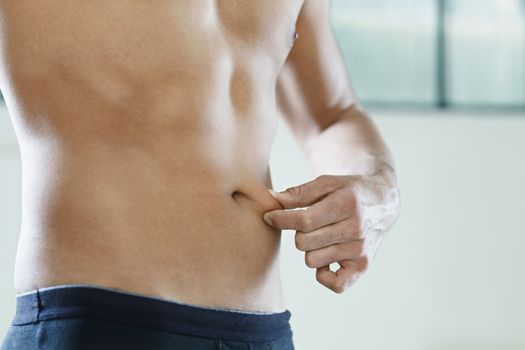 cropped view of young caucasian man measuring fat on belly. Horizontal shape, mid section, side view, copy space 