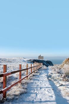 fenced walk to ballybunion castle in snow 