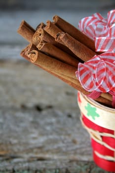 Cinnamon sticks in a christmas basket with red and white ribbon.