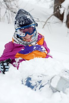Female skier sitting in the deep snow, smiling