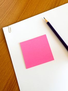 white paper with pencil and pink memo on table